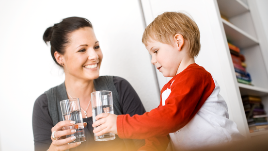 Mutter und Tochter mit Glas Trinkwasser