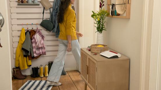 Frau geht durch einen Flur mit einem Glasfaser-Router Fritz!Box 5530 