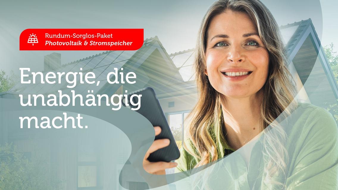 Frau mit Handy vor Haus mit Solaranlage